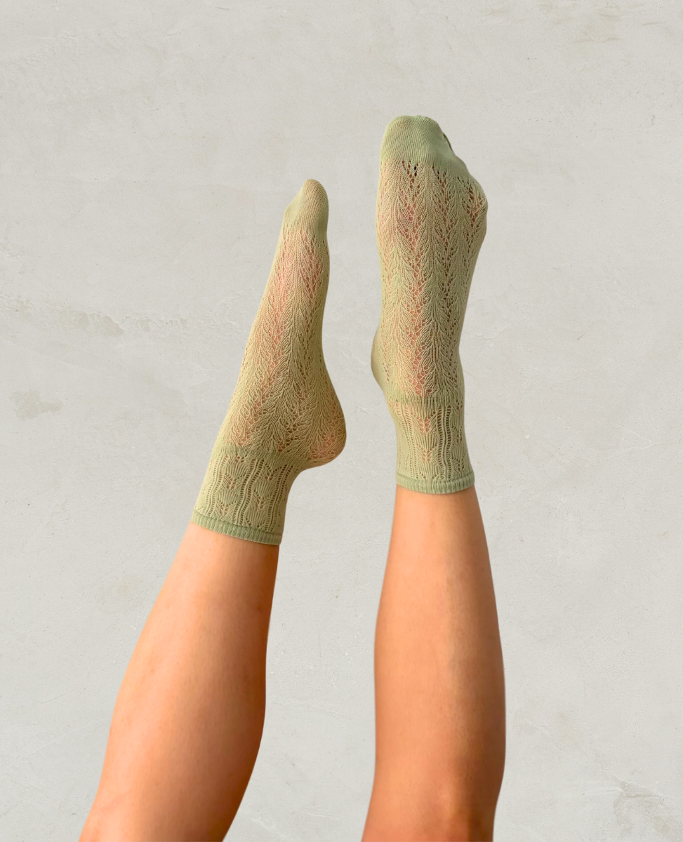 Mint green crochet socks by Swedish Stockings worn by a person on a light gray background
