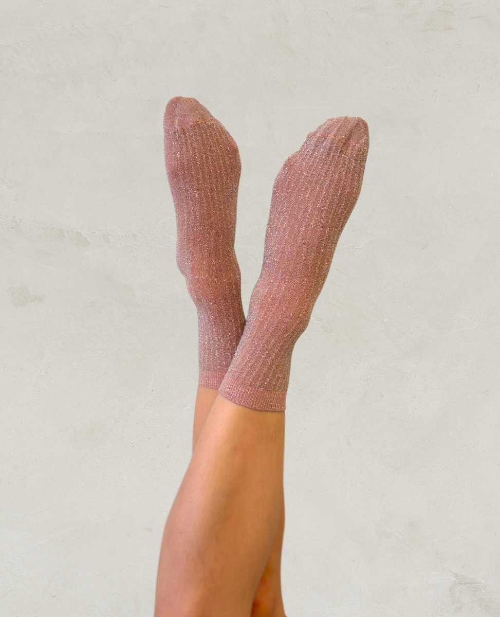 Pink shimmery glitter socks by Swedish Stockings worn by a person on a light gray background