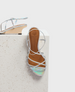 A sandal with iridescent silver straps, a tan footbed, and a low wooden wedge heel, featuring a minimalist design with crisscrossing straps. 1