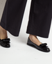 Black patent leather ballet flats with a glossy finish, featuring a distinctive large loop on the toe and a sleek, rounded shape. 4