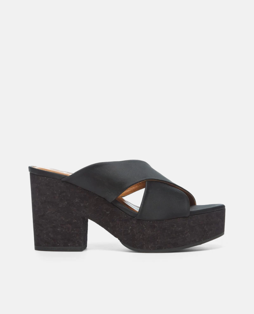 A black platform sandal featuring a thick, textured sole and heel, with a wide, smooth strap crossing over the top, creating an open-toe design.