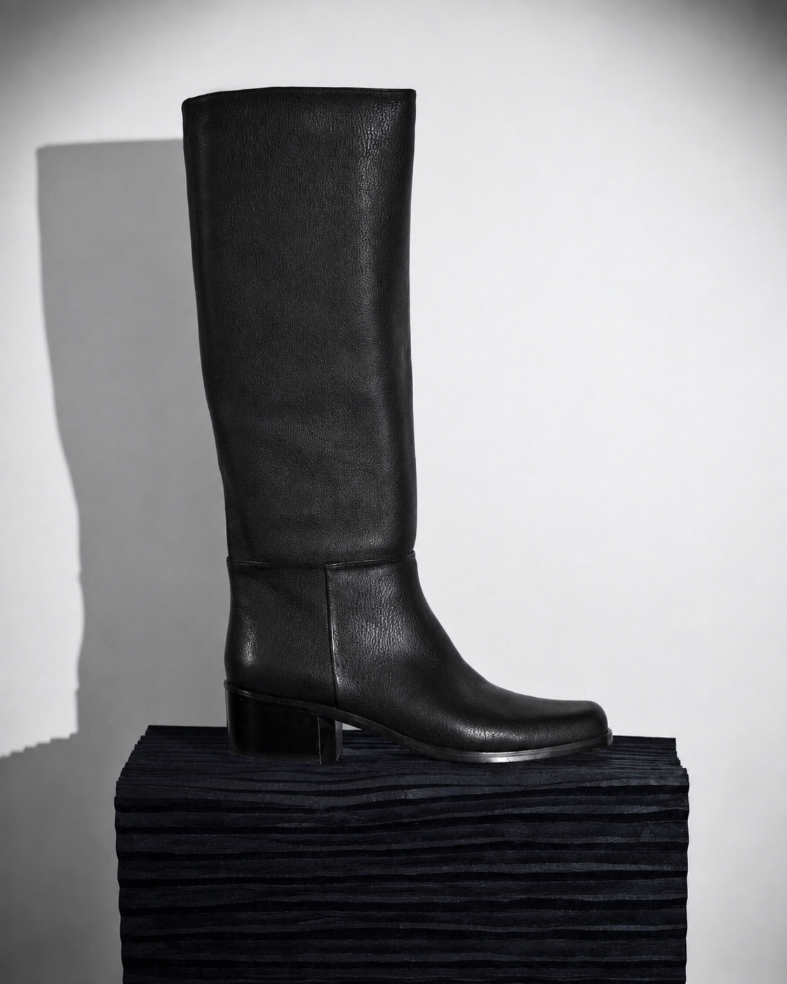 Coclico Alto Boot in black leather, worn knee-high with a low block heel