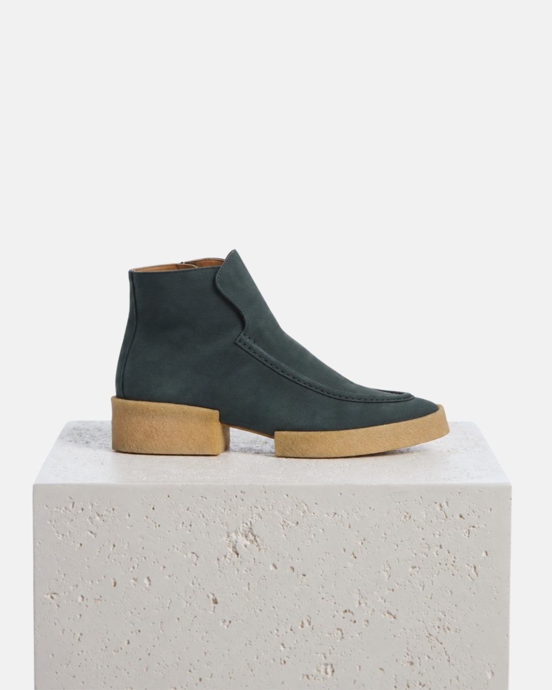 Coclico Boudica Boot in deep sea nubuck ankle boots with natural crepe soles styled on a stone plinth