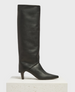 A sleek, black, knee-high boot with a pointed toe, smooth leather texture, and a mid-height stiletto heel, featuring a minimalist design with no visible embellishments. 2