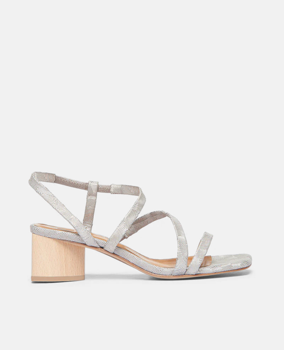 Coclico Shirin Heel in Platino Emboss (textured) leather: an open sandal with asymmetrical string-like straps across foot, solid mid-height wood heel - side view. 