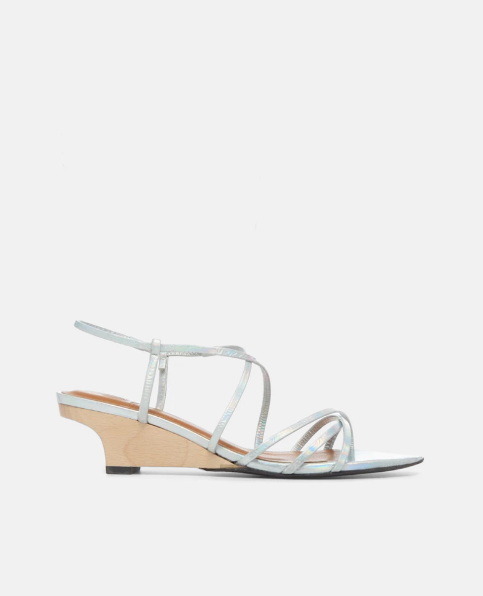 A sleek, silver strappy sandal with a low, light wooden wedge heel, featuring thin metallic straps and a minimalist design.