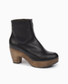 Angled view of the Tecla Clog in Black; featuring clean lines, snug fit, and curved solid wood platform heel make this clog boot a timeless classic. Inside zipper closure.Italian veg-tanned leather upper with solid wood 2