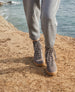 Legs of a woman wearing grey pants and the Hubby Boot in Fog while standing on a cliff with the ocean in the background.  8