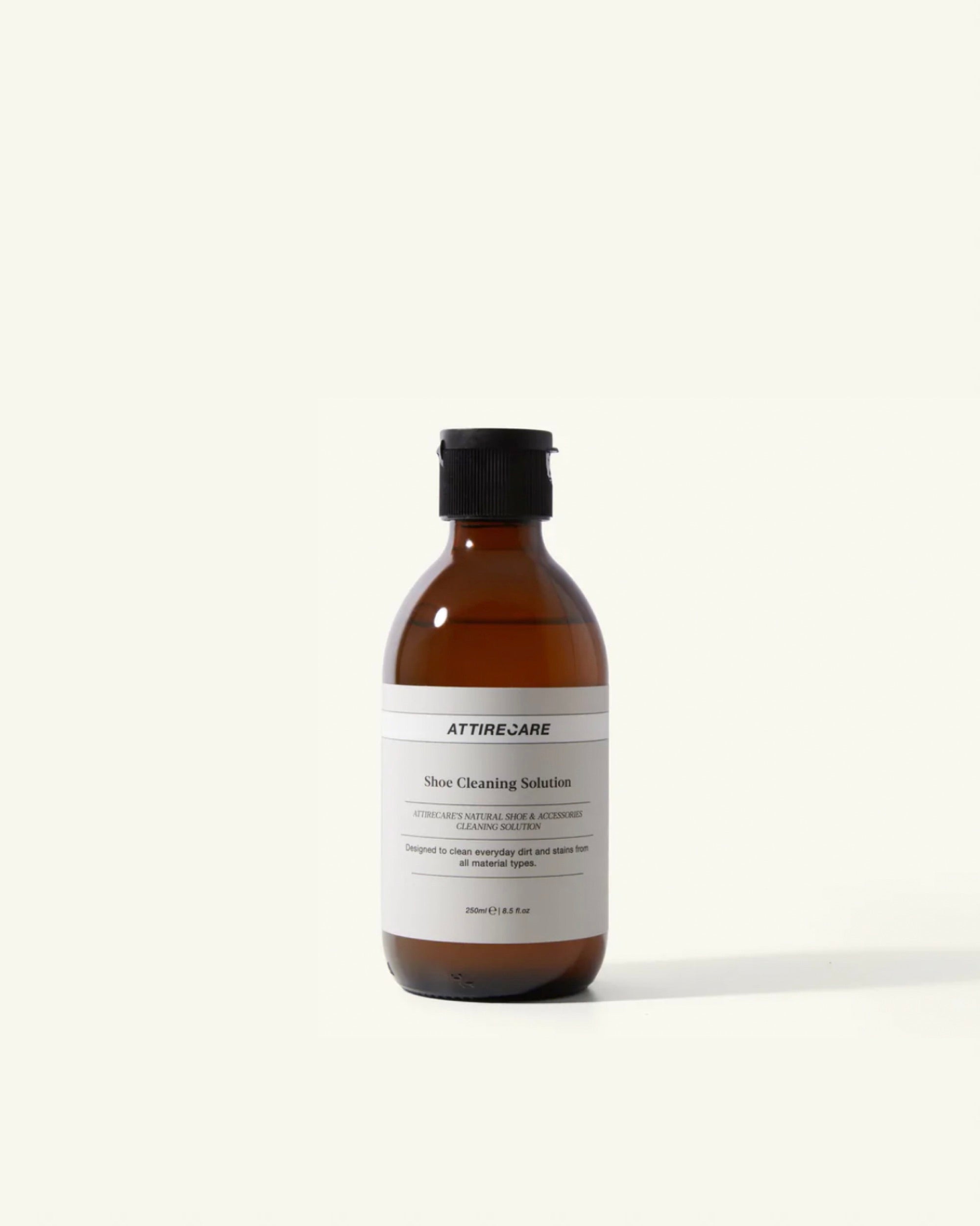 Brown bottle of shoe cleaning solution with a black cap on a white background