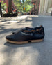 Side view of Coclico Alskling Flat in Black leather:  elasticated top line that hugs the foot, two-part .5 inch EVA sole, squared-off toe on NYC sidewalk.  7