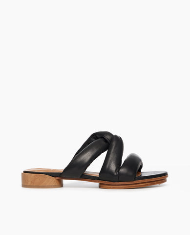 Side view of Coclico Everly Sandal in Black leather an open sandal with padded straps in a twist across arch, raised two-part leather sole.