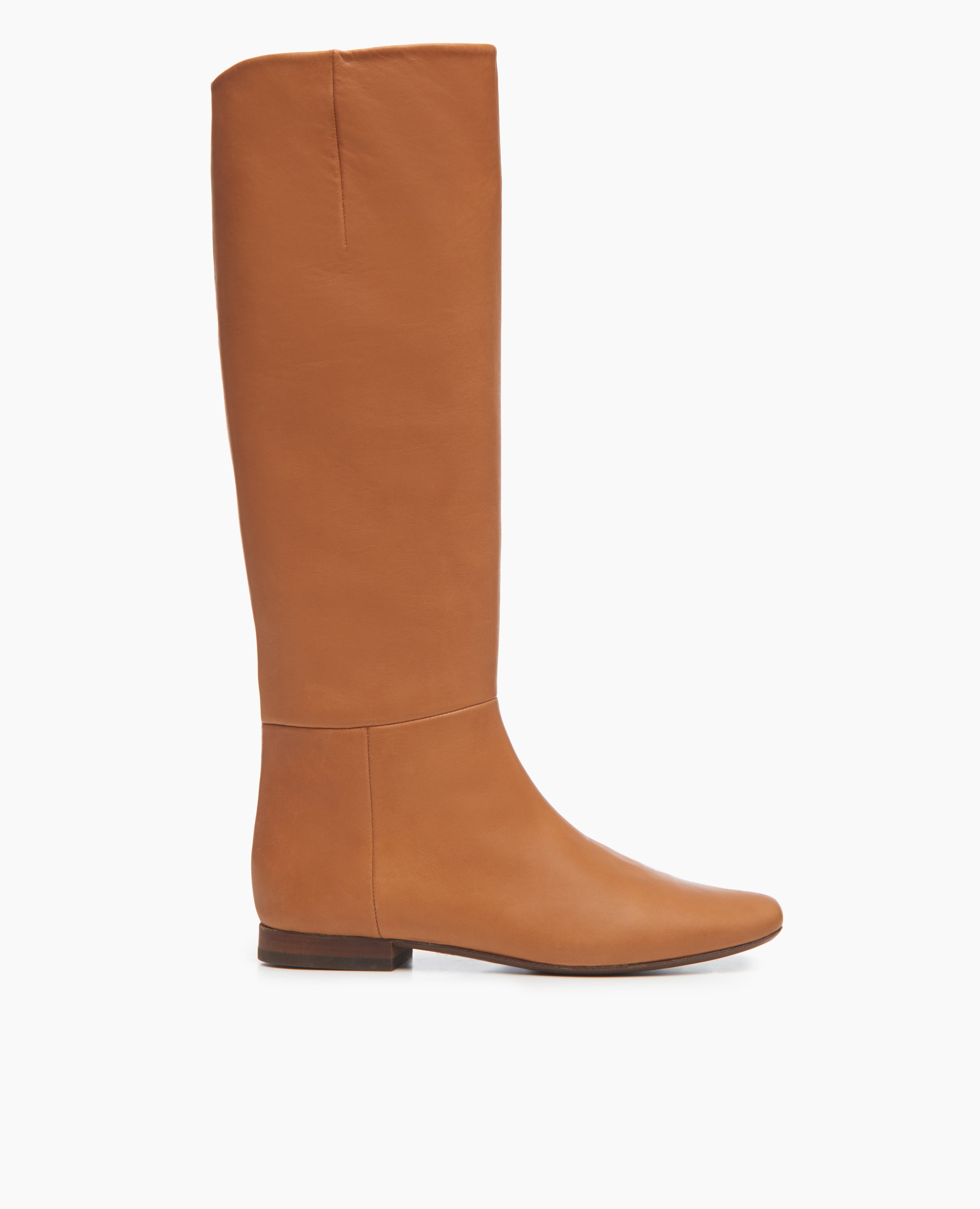 Side view of the Coclico Haricot Boot in Luggage leather: a flat-heeled, knee-high boot with an inside zip closure and  seam detailing. 