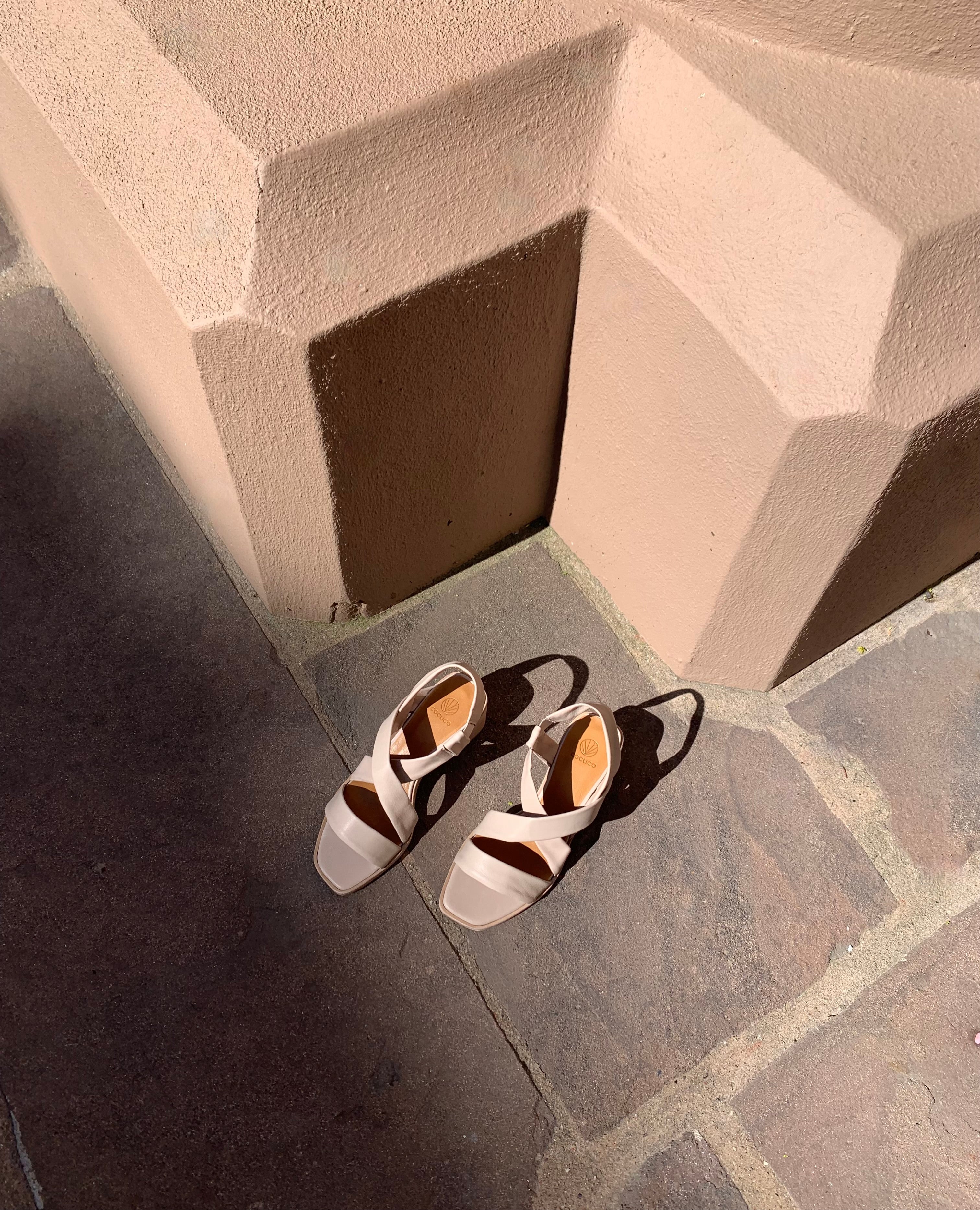Coclico Jade Heel in Grey Mist leather, top view: open slip on sandal with leather tube straps across the foot, sling-back strap, wood block mid-height heel - on tile flooring in sunlight.