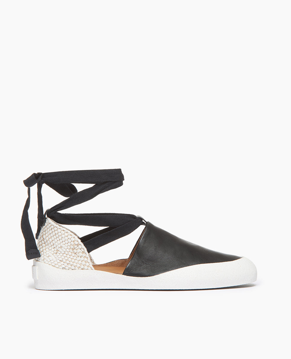 Coclico Kashm Sneaker in Black leather: a unique flat-like feel sneaker with recycled rubber sole, leather upper secured with wide cotton laces that wind around the ankle - side view. 