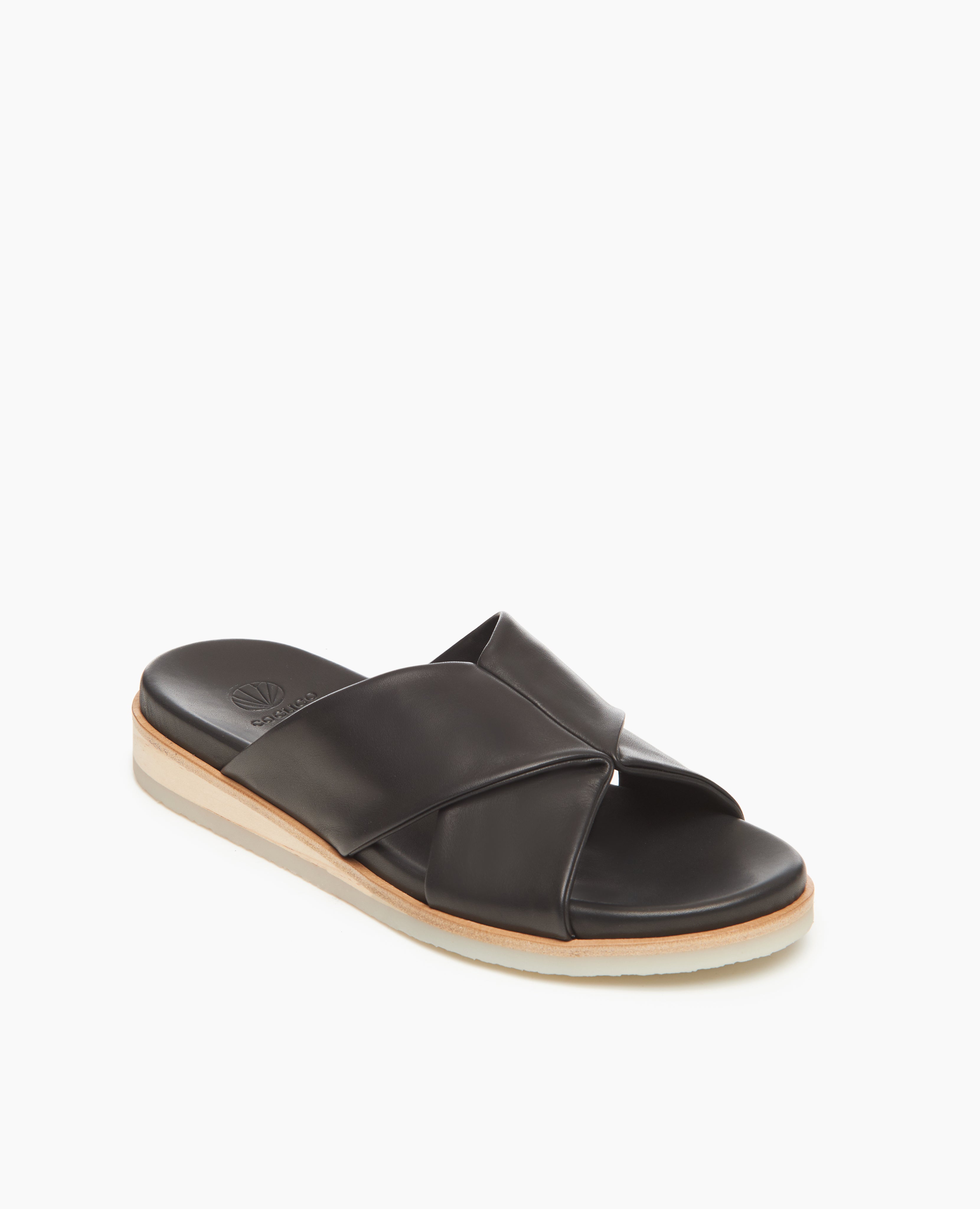 Coclico Pasque Sandal in Black leather, angle view: low pine wedge slide sandal, rubber sole, intertwined leather tube straps across foot. 