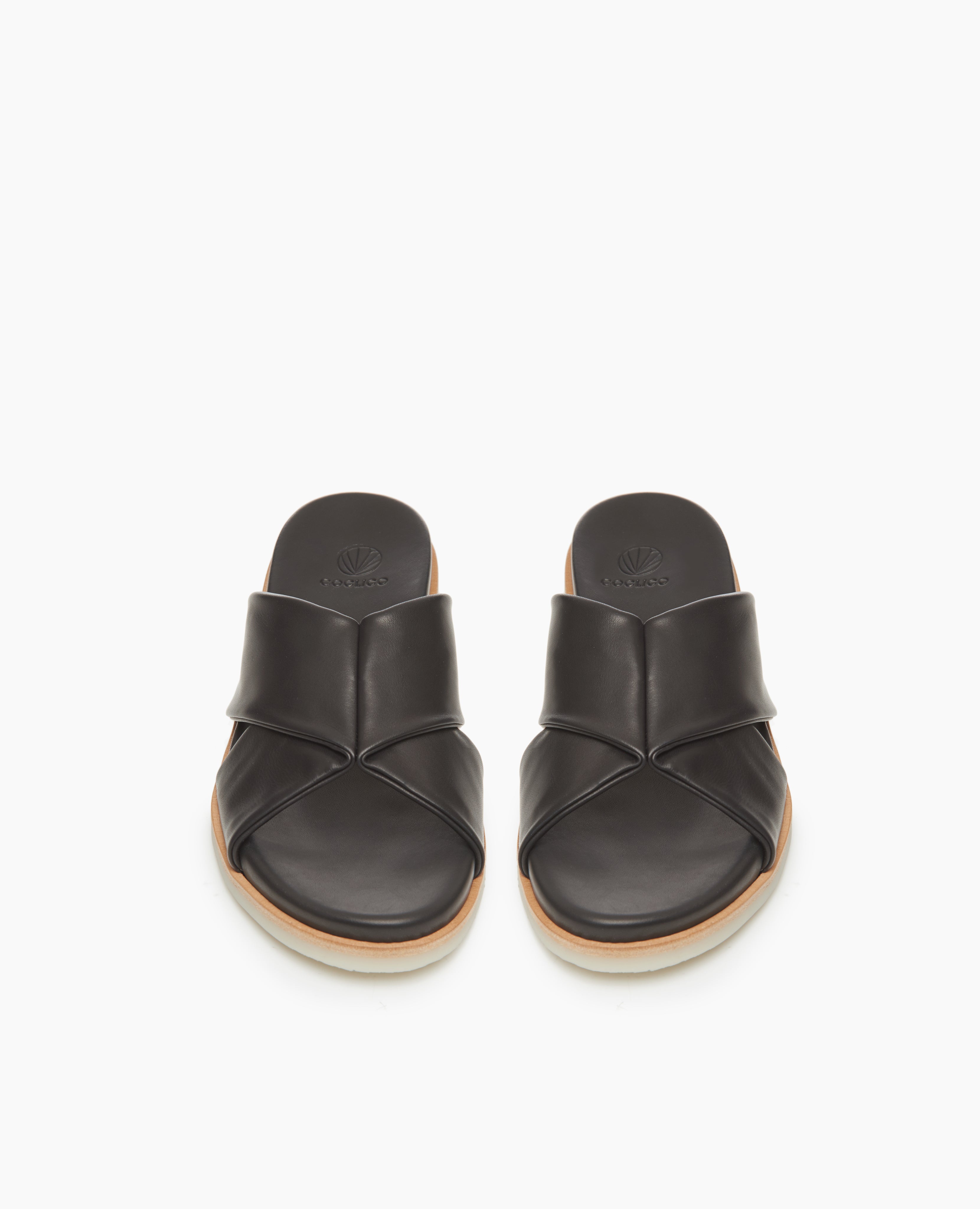 Coclico Pasque Sandal in Black leather, a low pine wedge slide sandal with rubber sole and intertwined leather tube straps across foot - top view. 