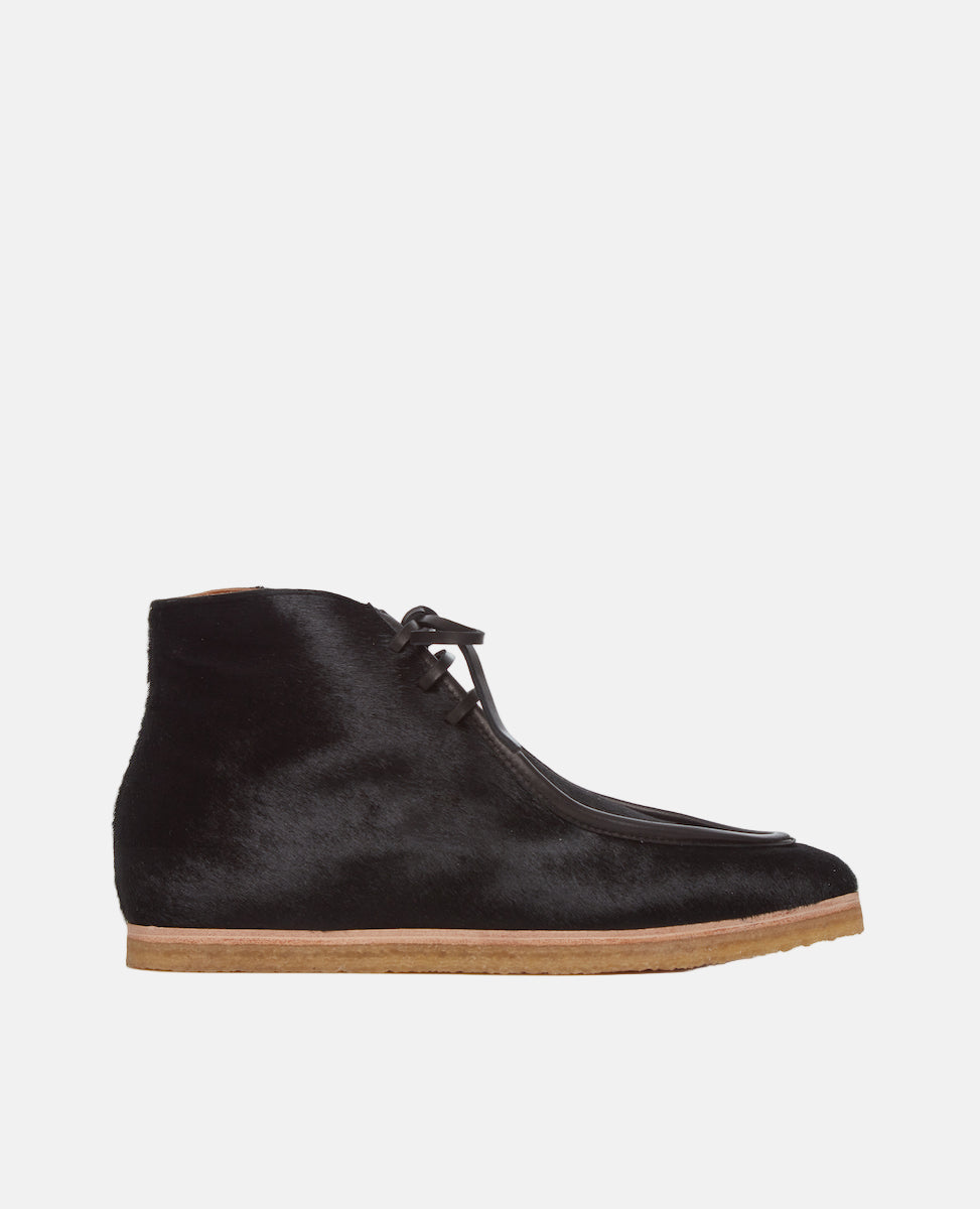 Side view of the Coclico Quinn Boot sophisticated chukka bootie in our limited edition black lux hair. Gentilly pointed moc toe, raised black leather piping and lace closure. Inside you'll discover a 30MM hidden wedge that adds height and comfort. 