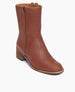 Coclico Sracha Boot in Caramello leather, angle view: a timeless boot with a low-height solid wood block heel, rounded toe and a decorative vertical strap that is placed opposite to the inside zip closure.  2