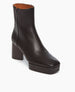 Angled view of the Travis Boot in Black: features a formed squared toe and balanced with a platform. Inside zip closure.  5