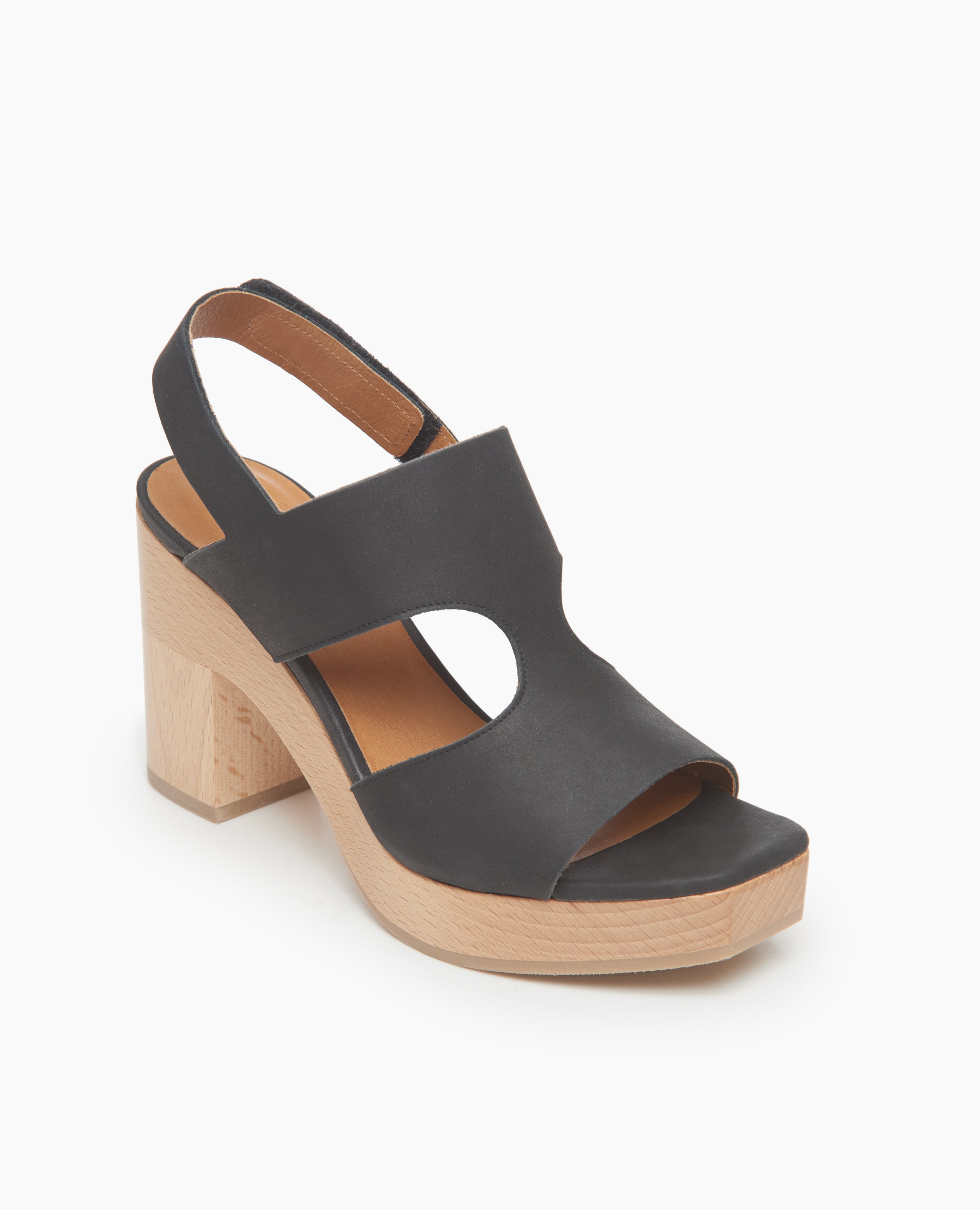 Coclico Vicky Clog in Black leather a t-straped clog with arched openings, angular toe, round heel and tall-height solid wood base - angle view. 