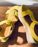 Close up of Coclico Ally Clog in Certosa suede: an open t-strap sandal on solid wood wedge platform, velcro closure on wooden table in sunlight.  6