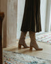 Woman modeling the Coclico Basil Boot in Limestone nubuck in hallway.  7
