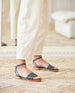 Close up of woman modeling Coclico Erren Sandal in Deep Sea leather an open sandal with leather front band, raised two-part wood and leather sole, tubular ankle strap that crisscrosses behind the heel - angle view. 2