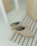 Coclico Kera Shearling Clog in Latte nubuck, a slip-on mule with a mid-height wood block base, tapered toe, shearling lining - top view shot of mules on carpet.  2