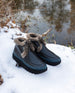 Pair of the Fiona Shearling Bootie in Deep Sea placed outside on top of snow with a lake behind.  5