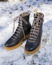 Pair of Heaven Shearling Boot in Black placed on top of snow. Angled.  2