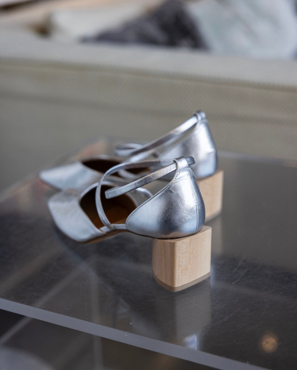 Behind view of a pair of Isabel Mary Jane shoes in Milky Way on top of a clear acrylic table. 