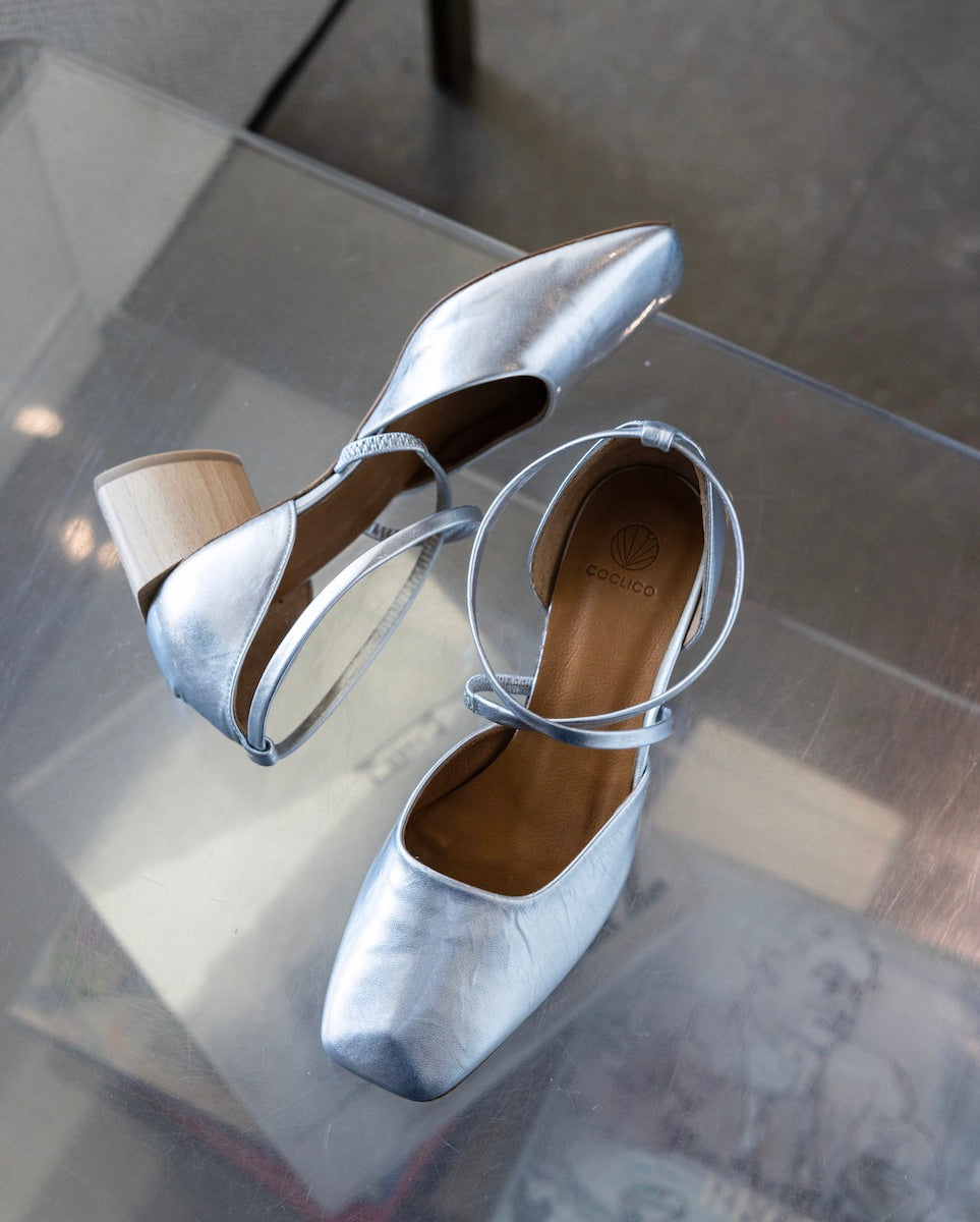 Top view of a pair of Isabel Mary Jane in Milky way resting on top of a clear, acrylic table. 