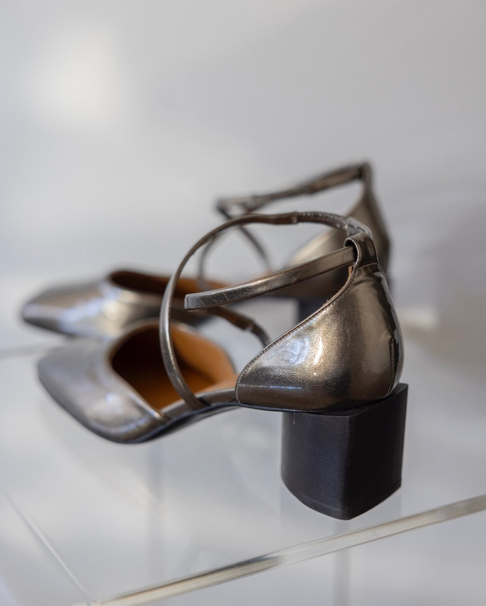 Back angled view of a pair of the Isabel Mary Jane in Starry Night resting on a clear, acrylic table. 