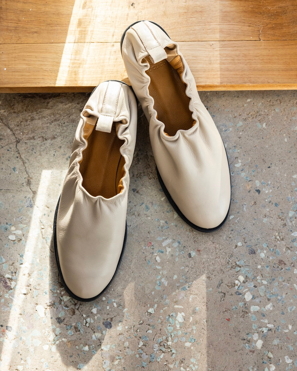 Yano Flat in Grey Mist on a sunny, wooden ledge and terrazzo flooring. 
