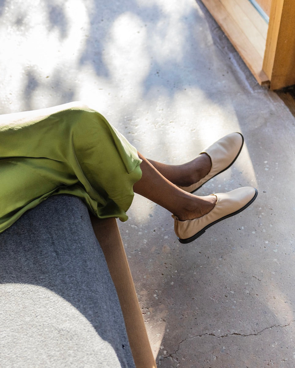 Woman's legs seated and wearing the Yano Flat in Grey Mist.