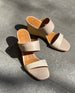 Top view of Coclico Doe Wedge in Greige & Marmo leather in natural sunlight: a two-neutral-toned slide, asymmetric straps, solid wood mid-height wedge. 8