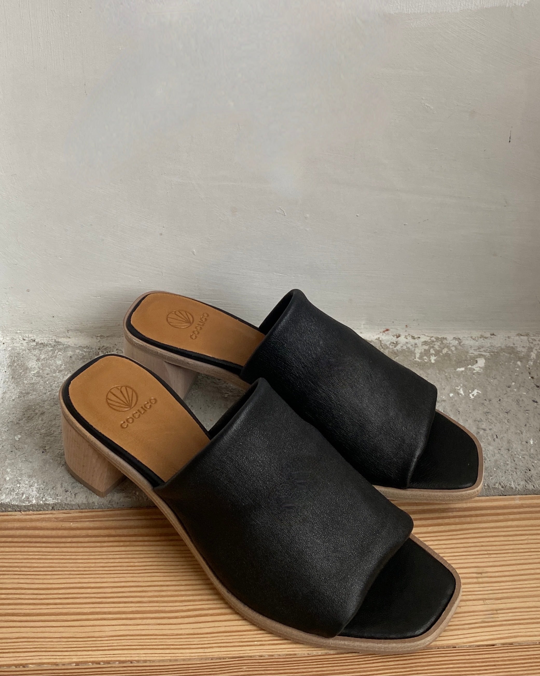 The Jacque Heel in Black leather a slide-on style with a stretch leather band across foot and a wood block mid-height heel.