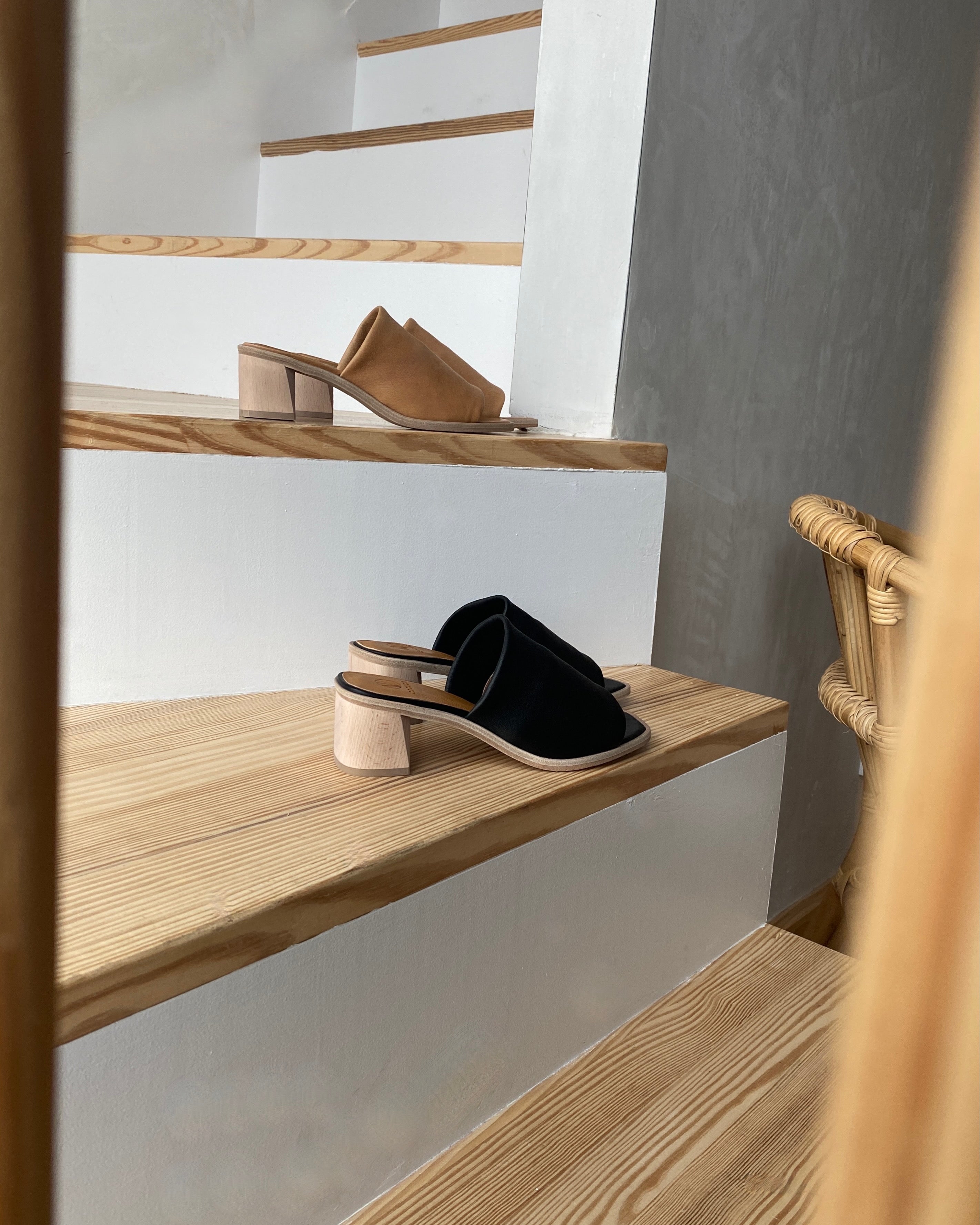 Coclico Jacque Heel in Black leather and Mandorla leather displayed on a staircase - side view. 