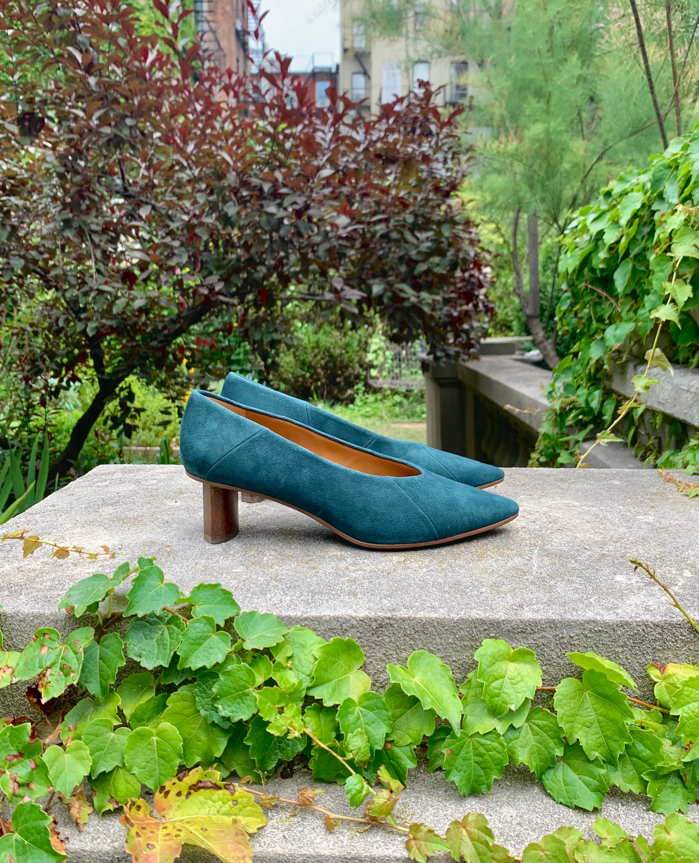 Side view: Coclico Wumo Heel in Bottle suede - with greenery in background.
