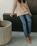 Woman leaning on a ledge while wearing jeans styled with the Bani boot in Tobacco suede.  7