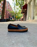 Side view shot of Coclico Gentian Flat in Black leather: a slip-on flat with leather band and .5 inch rubber EVA sole - on NYC sidewalk.  6
