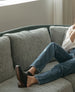 View of women's upper body and legs laying on a couch wearing jeans and a white shirt with the Kera Shearling Clog 5