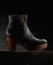 Side view of the Tecla Clog in Black with a dark background.  5